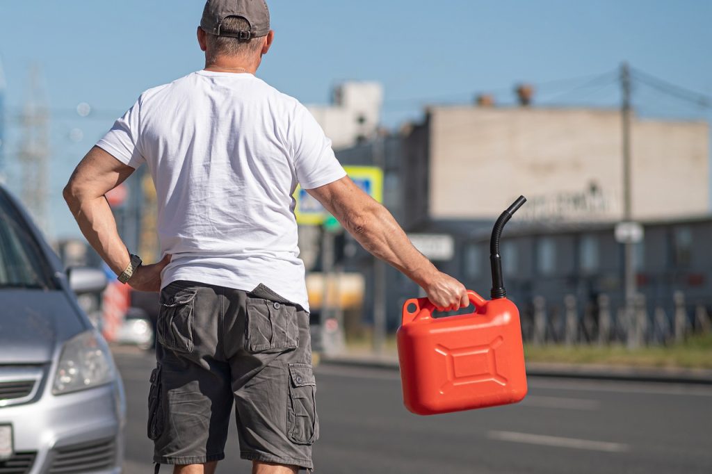 man carrying a gas can because his car has run out of fuel
